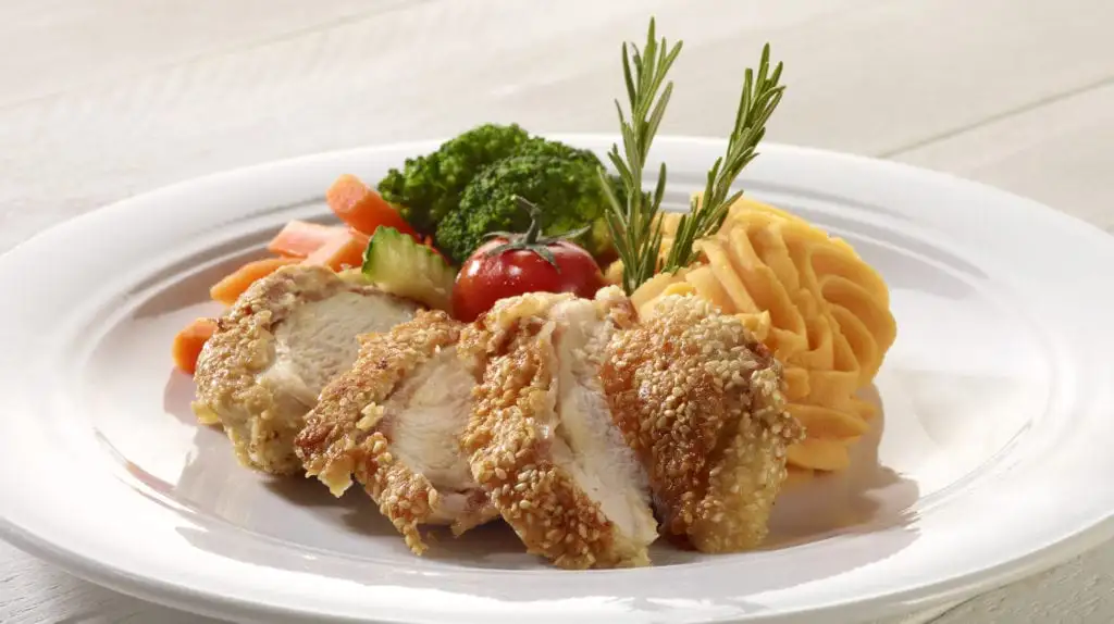 Ein Teller mit Hähnchen, Karotten und Kartoffeln, appetitlich angerichtet.