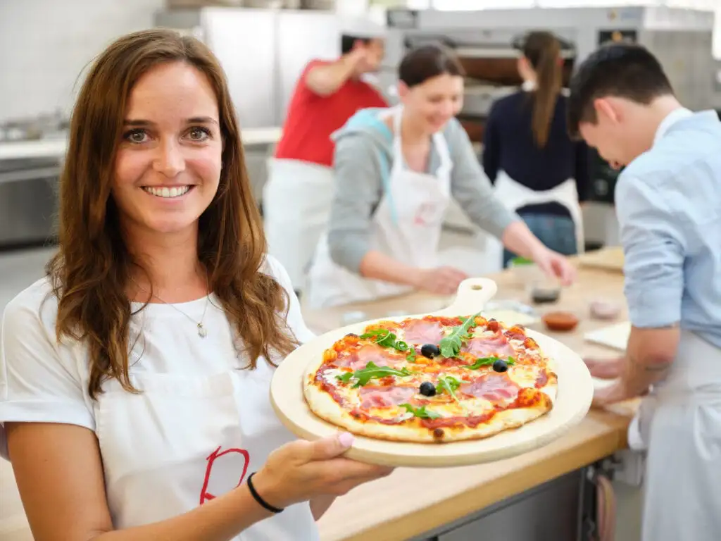 Eine Frau hält eine Pizza in einer modernen Küche.